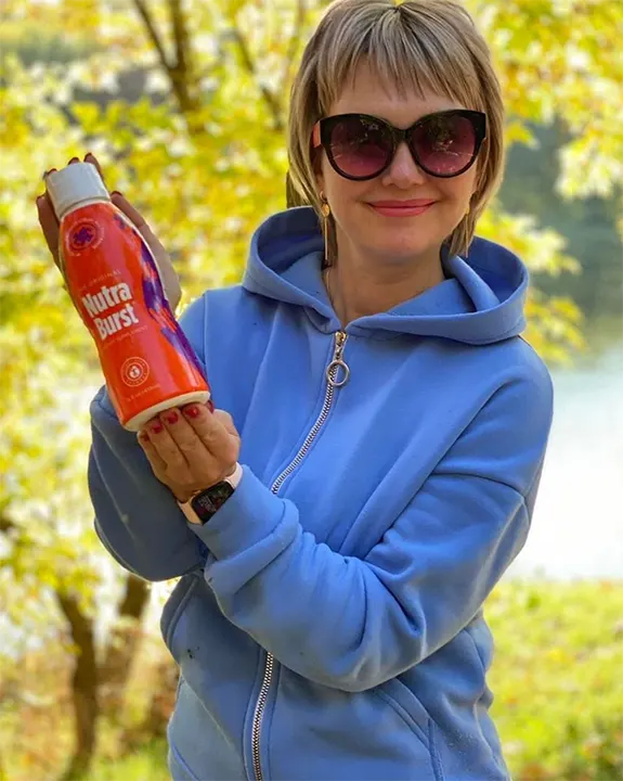 Smiling Woman in blue hoodie holding NutraBurst