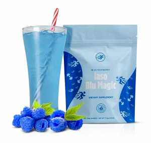 A glass and pack of Blu Magic next to blue raspberries