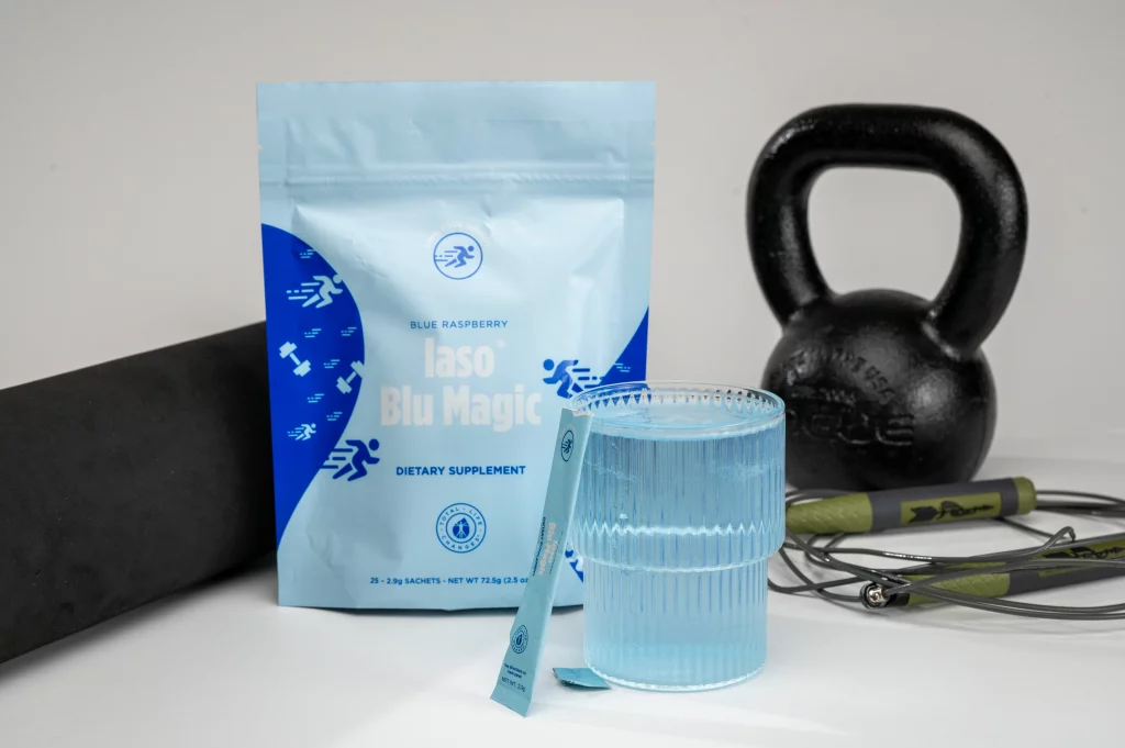A glass and pack of Blu Magic alongside a yoga mat, kettlebell, and jump rope