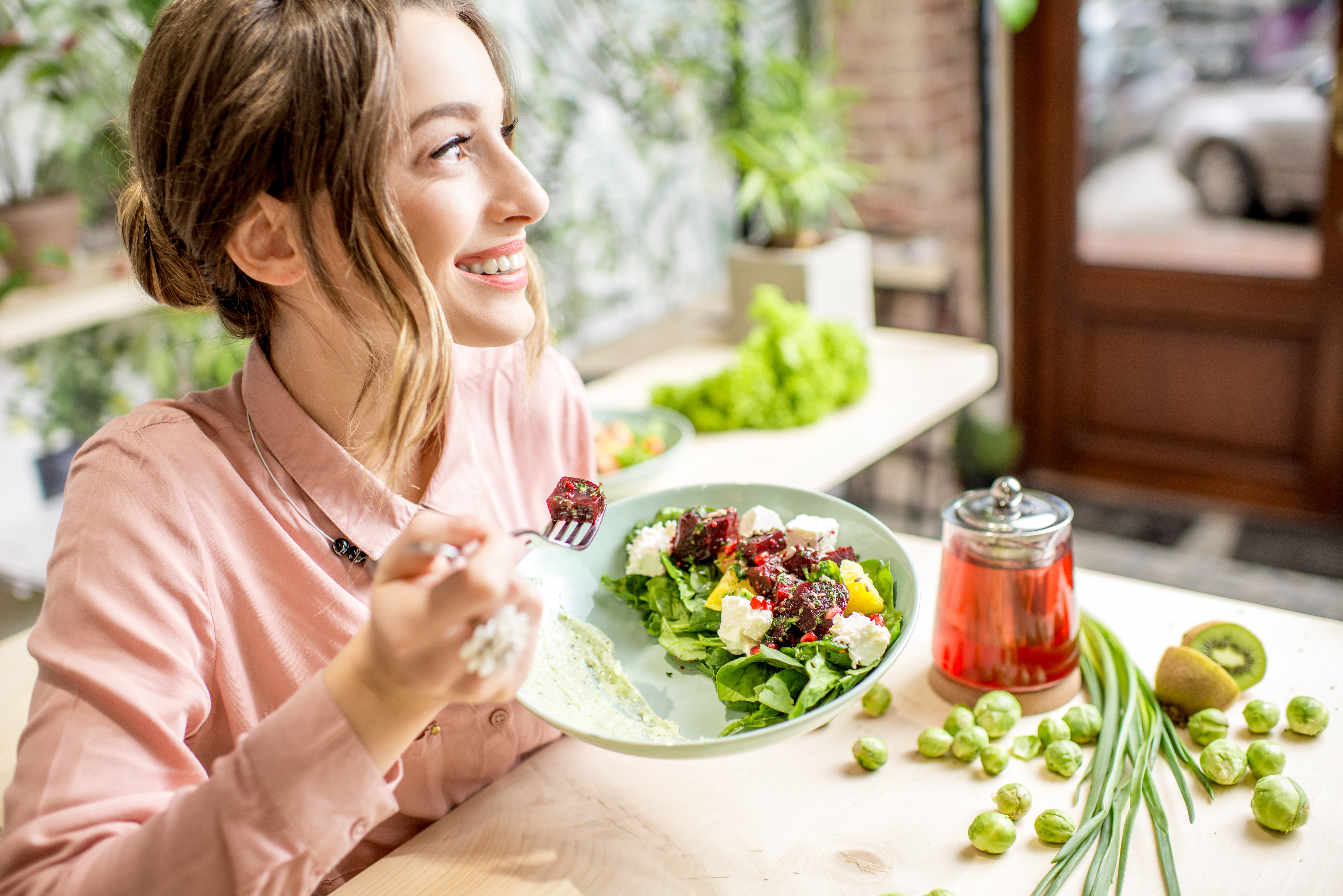 Young woman sitting at a table eating a salad
